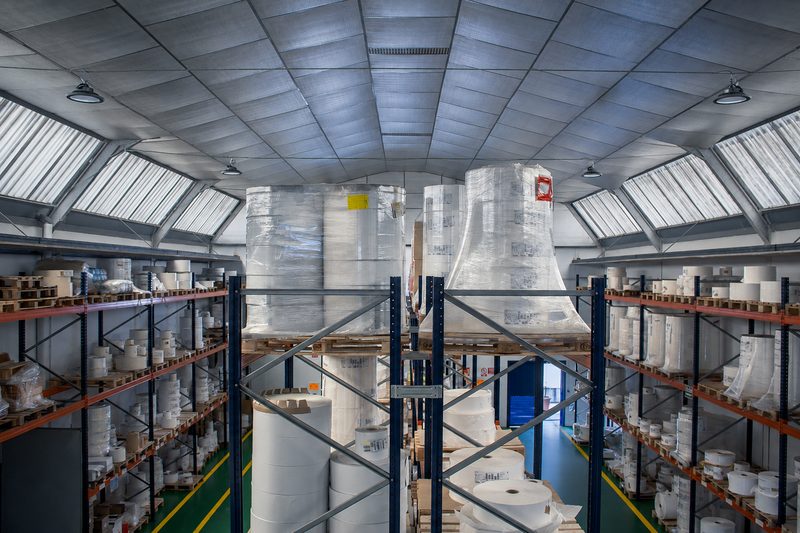 Almacén de bobinas de papel y material adhesivo, en estanterías de dos alturas
