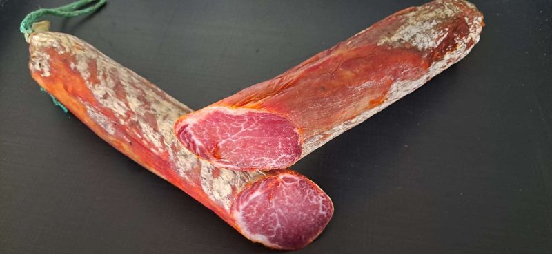 Lomo ibérico entero y en corte sobre fondo oscuro