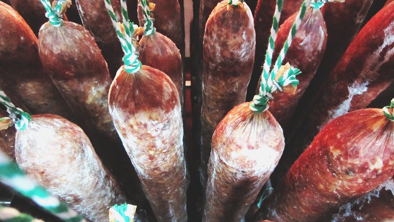 Embutidos ibéricos atados y colgados durante la curación